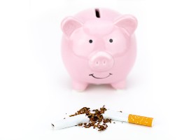 pink piggy bank with a broken cigarette in front of it. white background.